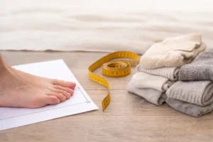 Pomiar długości stopy w celu dobrania odpowiedniego rozmiaru skarpetek dla dzieci i dorosłych.